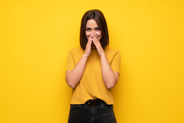 Young woman over yellow wall smiling a lot
