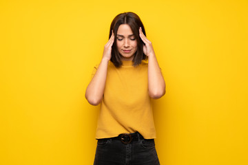 Young woman over yellow wall with headache