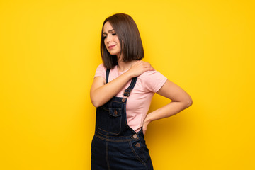 Obraz premium Young woman over yellow wall suffering from pain in shoulder for having made an effort