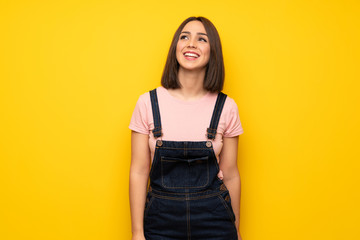 Young woman over yellow wall smiling