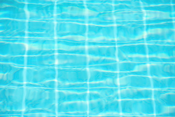 The blue water waves by wind and sunlight reflecting surface In the swimming pool.