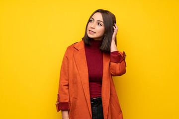 Young woman with coat thinking an idea while scratching head