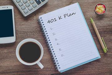 401K Plan text on book note with cup of coffee, pen and smartphone.