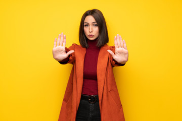 Young woman with coat making stop gesture and disappointed