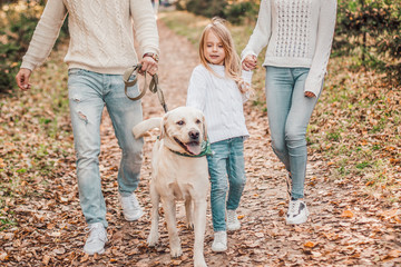Fototapeta premium Happy beautiful family with dog labrador is having fun together walking the in park.
