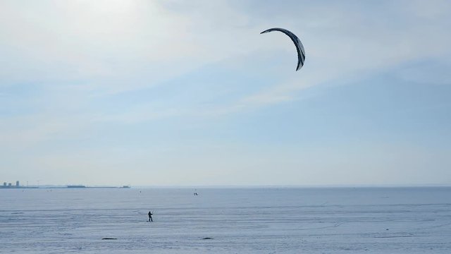 a snowboarder with a parachute rides around the bay in the city of St. Petersburg