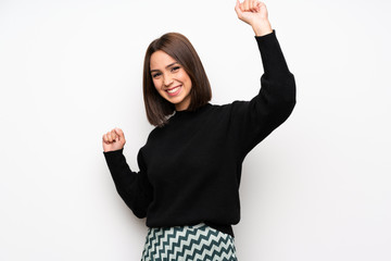 Young woman over white wall celebrating a victory in winner position