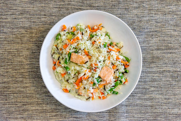 Top view wild salmon fried rice with white cream on white ceramic dish on textile sofa.  