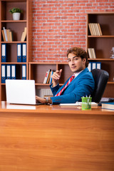 Young handsome employee sitting in the office  