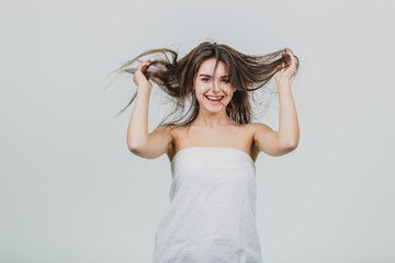 Naklejka premium Forgetting that I am an adult. Playful, happy and children's attractive female rough hair, smiling widely, holding hands with the assistant and pulling her hair down, playing with the sling, as if