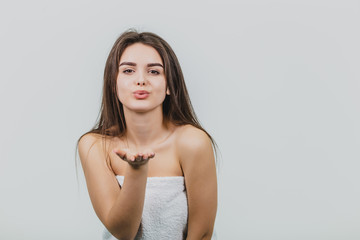 Fototapeta premium Beautiful young girl with smooth skin on a light background with natural make-up and curly dark hair.