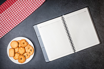 Cookies on Plate and Diary book with Black stone table background.