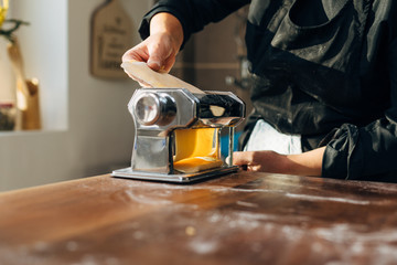 Female chef making pasta. Kneading rolling. Pasta maker
