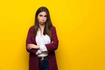 Young woman over yellow wall with sad and depressed expression