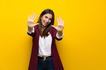 Young woman over yellow wall counting ten with fingers