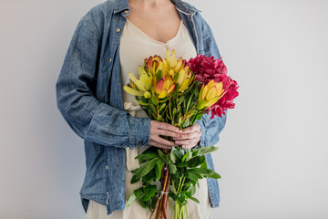 Female hands holding bouquet of peonies and  Leucadendron
