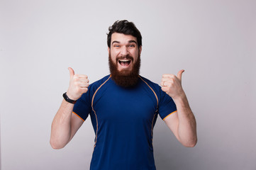 Happy funny bearded man showl like sign thumbs up and good like, on white wall background