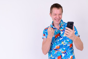 Portrait of young happy tourist man using phone and getting good news