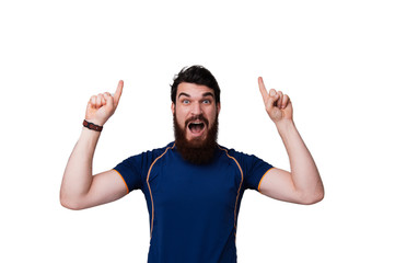 Fototapeta premium Portrait of excited bearded man in checkered shirt pointing fingers up over white background