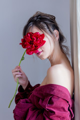 Female in red shirt holing red peony