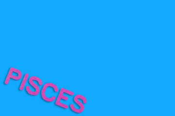 Word pisces cut out of purple paper on blue table. Top view. Horoscope concept