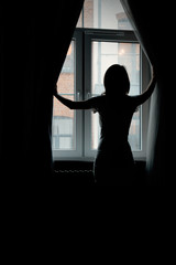 a young girl looks behind the curtains