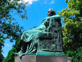 Austria. Sculpture of Johann Wolfgang von Goethe in Vienna on blue sky and surrounded by green...