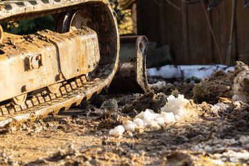 An excavator works in the garden, removing a root