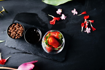 Fresh Strawberries in glass, .rice flakes, and chocolate, on black stone board.