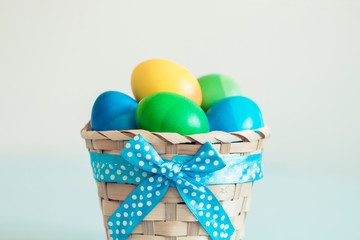 ombre colored easter eggs in a wicker basket with blue ribbon