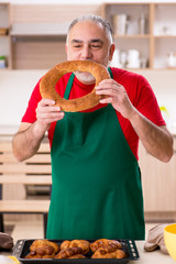 Old male baker working in the kitchen 