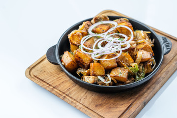 Fried potatoes with meat, broccoli and red onions decorated with rosemary in a frying pan on a wooden table top view