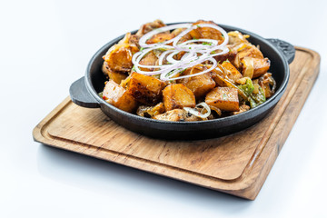 Fried potatoes with meat, broccoli and red onions decorated with rosemary in a frying pan on a wooden table top view