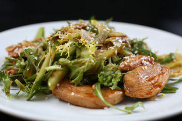 salad of a large amount of greens, green celery, arugula, boiled meat fillet with sauce and sesame