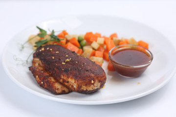 chicken fillet, baked with spices and covered with an appetizing crust, on a plate with vegetables and sauce