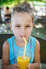 Fototapeta premium beautiful boy is drinking orange juice 