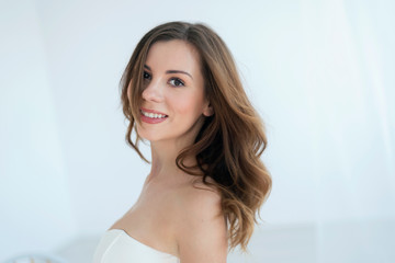 Expression photo of smiling brunette in white dress, on white background. Concept of delicacy, chastity and innocence of woman. - obrazy, fototapety, plakaty