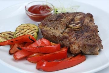 Beef kebabs on a plate with grilled vegetables, zucchini and Bulgarian red pepper, decorated with greens