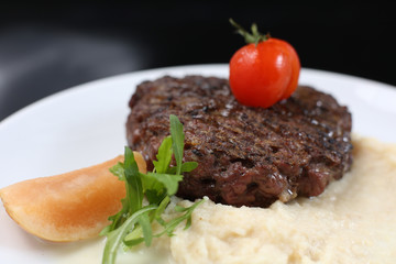 fried meat cutlet on a plate, with celery puree, garnished with tomato cherry and sour apples, isolated