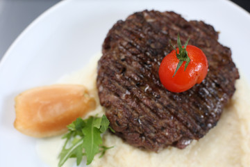 fried meat cutlet on a plate, with celery puree, garnished with tomato cherry and sour apples, isolated