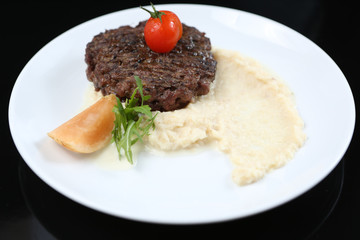fried meat cutlet on a plate, with celery puree, garnished with tomato cherry and sour apples, isolated