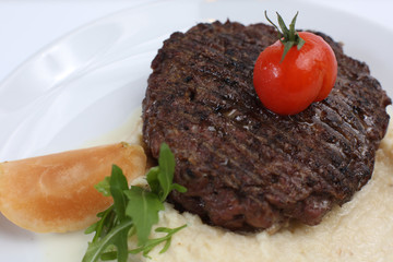 fried meat cutlet on a plate, with celery puree, garnished with tomato cherry and sour apples, isolated