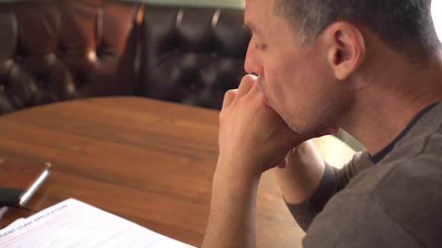 Unhappy sad man reading letter, bill, bank statement paper or tax document