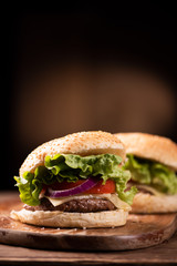 Tasty grilled beef burger with lettuce, cheese and onion served on cutting board with copyspace