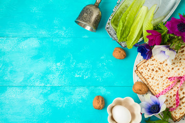 Jewish holiday Passover background with matzo, seder plate and spring flowers on wooden table.