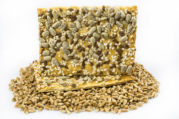 Cookies from cereals  and seeds lies among the grains of  wheat. Isolated on a white background.