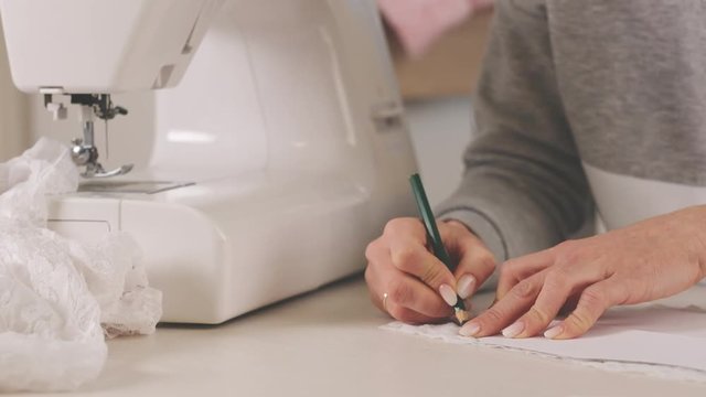 Proffesional seamstress making pettern with pencil
