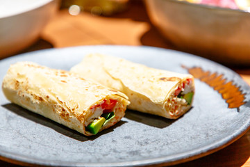 The Shawarma is wrapped in pita bread two piece lies on a plate