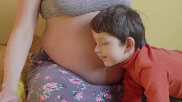 little boy listening to mom pregnant belly