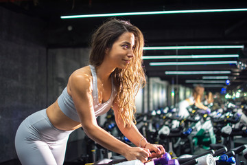 Fototapeta premium Side view profile on beautiful young woman riding on the spinning bike at gym
